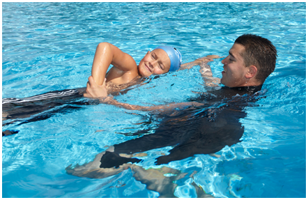 Male swimming instructor training a young student in-water