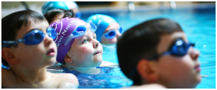 Young school children wearing goggles having a swimming lesson in a pool