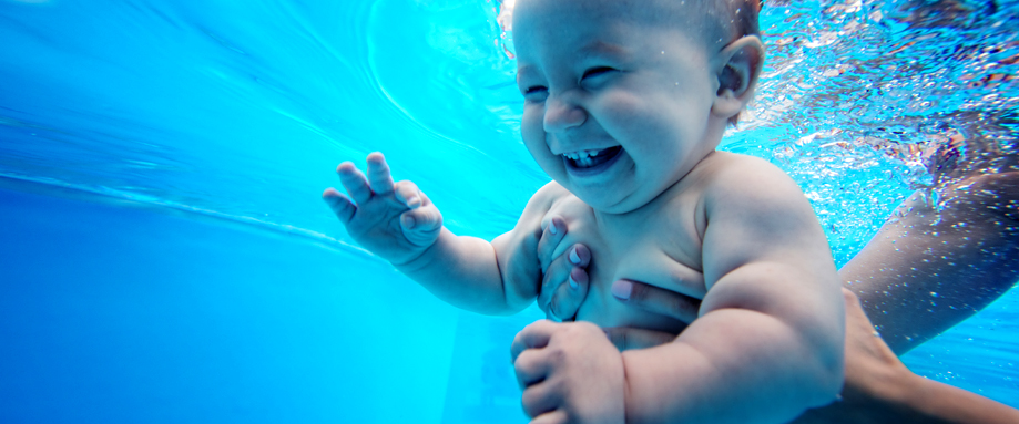 Female instructor supporting a baby in a pool during a swimming lesson